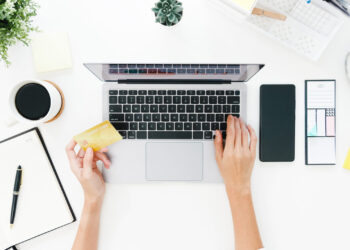 Top view of freelance Asia lady casual using laptop online shopping with credit card on table in living room at house. Working from home, remotely work, social distancing, quarantine for coronavirus.